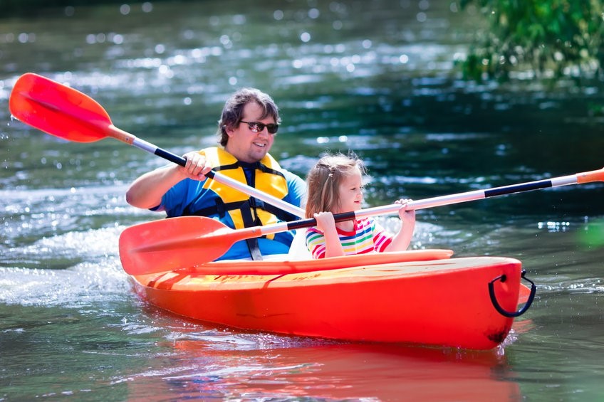 Family on kayaks and canoe tour. Father and child paddling in kayak in a river on a sunny day. Children in summer sport camp. Active preschooler kayaking in a lake. Water fun during school vacation.